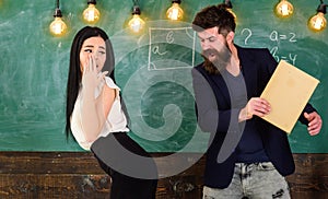 Man with beard slapping student, chalkboard on background. Girl on helpless face punished by teacher. Schoolmaster photo