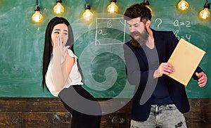 Man with beard slapping student, chalkboard on background. Girl on helpless face punished by teacher. Schoolmaster