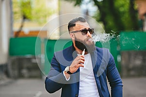 Man with a beard smokes electronic cigarette