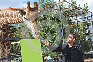 Man with a beard stroking the head of a giraffe