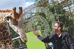 Man with a beard stroking the head of a giraffe