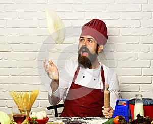 Man with beard throws pizza dough up on white background