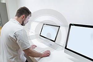 Man with a beard uses a computer monoblock with a white screen in a technology store