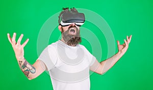 Man with beard in VR glasses, green background. Power concept. Hipster on shouting face raising hands powerfully while