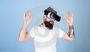 Man with beard in VR glasses, light blue background. Hipster on busy face exploring virtual reality with modern gadget