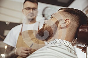 Man with beard waits for a shave with a razor in a barbershop