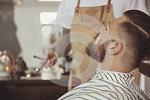 Man with a beard waits for a shave with a razor in a barbershop
