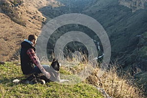 A man with a beard walking his dog in the nature, standing with a backlight at the rising sun, casting a warm glow and