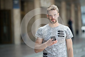 Man with beard walks with smartphone urban background. Guy use smartphone to send message or find location. Man use