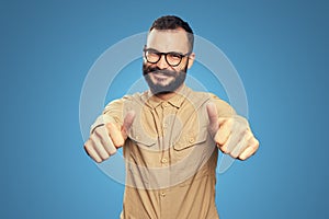 Man with beard wearing glasses and showing thumbs up happily on blue