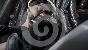 Man with beard, wearing glasses, white helmet stands in a boiler room