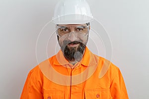 Man with beard wearing worker uniform and hardhat smiling looking at the camera