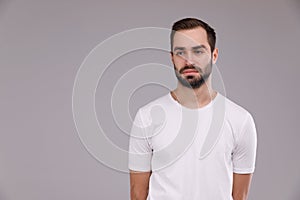 A man with a beard in a white T-shirt on a grey background