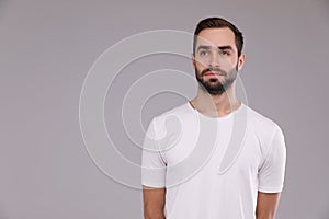 A man with a beard in a white T-shirt on a grey background