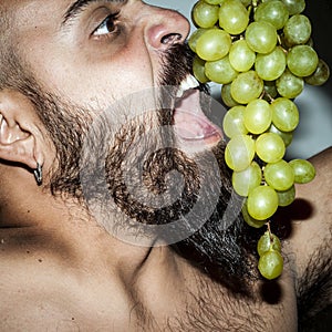 Man with beard who eats voraciously grapes