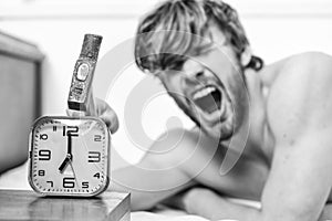 Man bearded annoyed sleepy face lay pillow near alarm clock. Break discipline regime. Stop ringing. Annoying sound