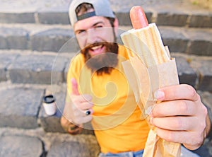 Man bearded enjoy street food stairs background. Hipster eat hot dog and drink coffee. Lunch time concept. Hipster enjoy