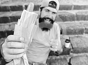 Man bearded enjoy street food stairs background. Hipster eat hot dog and drink coffee. Lunch time concept. Hipster enjoy