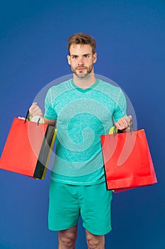 Man bearded face holds shopping bags. Guy bought lot sporty clothes and accessories. Man shopping on black friday. Guy