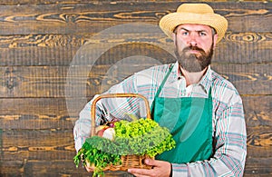 Man bearded farmer presenting eco vegetables wooden background. Farmer straw hat deliver fresh vegetables. Farm delivery