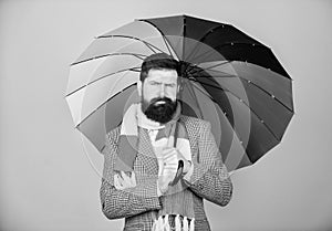 Man bearded guy hold colorful umbrella. It seems to be raining. Rainy days can be tough to get through. Prepared for