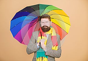 Man bearded guy hold colorful umbrella. It seems to be raining. Rainy days can be tough to get through. Prepared for