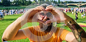 Man bearded hipster in front of crowd people show heart gesture riverside background. Hipster happy celebrate event