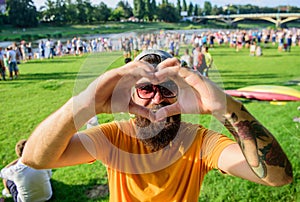 Man bearded hipster in front of crowd people show heart gesture riverside background. I love summer holiday festival