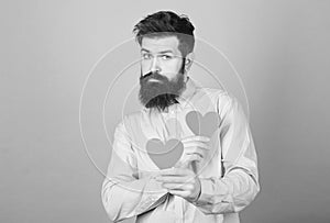 Man bearded hipster with heart valentine card. Celebrate love. Guy attractive with beard and mustache in romantic mood