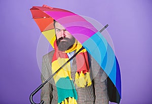 Man bearded hipster hold colorful umbrella. It seems to be raining. Rainy days can be tough to get through. Prepared for