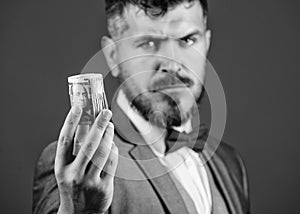 Man bearded hipster hold rolled dollars banknotes. Guy formal suit offer bribe or purchase. Hipster offer money blue