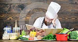 Man bearded hipster read book recipe near table fresh vegetables. Culinary arts. Recipe to cook healthy food