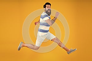 Man bearded hipster run yellow wall. Guy beard striped shirt. Freedom jump. Sale and discount. rush hour. lets go