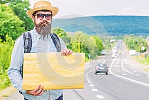 Man bearded hitchhiker stand at edge of road with blank paper sign, copy space. Benefits using sign with name