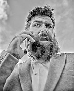 Man bearded surprised businessman hold mobile phone sky background. Hipster smartphone call partner. Man mobile call