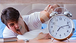 Man in bed frustrated suffering from insomnia with an alarm cloc