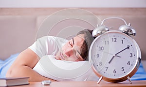 Man in bed frustrated suffering from insomnia with an alarm cloc