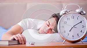 Man in bed frustrated suffering from insomnia with an alarm cloc