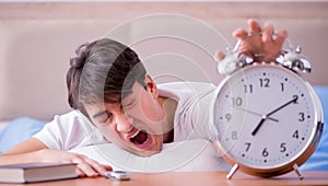 Man in bed frustrated suffering from insomnia with an alarm cloc