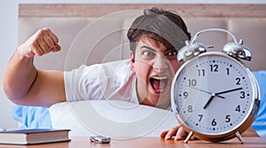 Man in bed frustrated suffering from insomnia with an alarm cloc