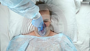 a man on a bed in a hospital whom the doctor gives a mask with anesthesia