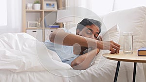 Man in bed with medicine and glass of water