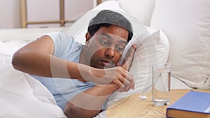 Man in bed with medicine and glass of water