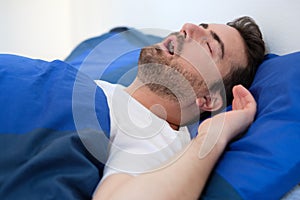 Man in bed suffering for sleep apnea syndrome