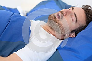 Man in bed suffering for sleep apnea syndrome