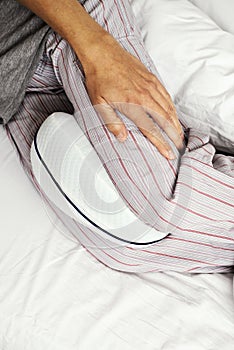 Man in bed using an anatomical leg cushion
