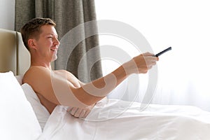 Man In Bed Watching Television And Holding Tv Remote