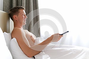 Man In Bed Watching Television And Holding Tv Remote