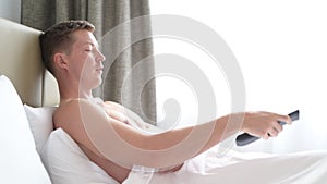 Man In Bed Watching Television And Holding Tv Remote