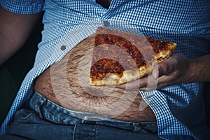 Man with a beer belly eating pizza